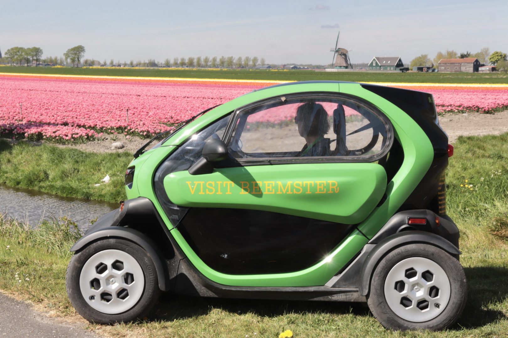 Twizy voor bollenland op achtergrond korenmolen De Nachtegaal